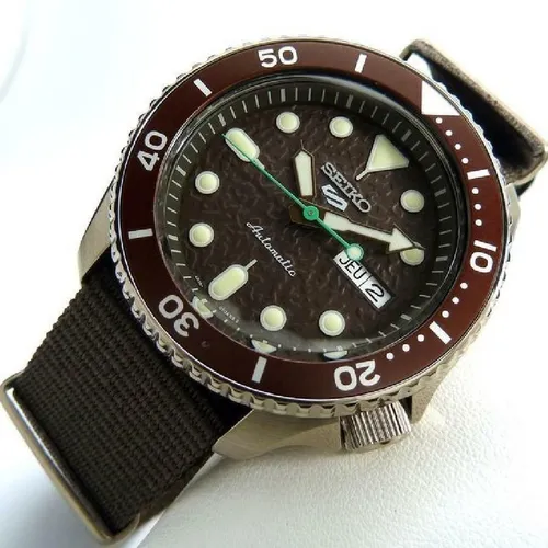 Seiko 5 SRPD85K1 Herren Automatikuhr - Braun/Braun - Herrenuhren mit Automatikwerk 4R36 und 41 Stunden Gangreserve. Wasserdicht bis 10 bar, ausgestattet mit robustem Nylonarmband und lumineszierenden Zeigern für optimale Ablesbarkeit.